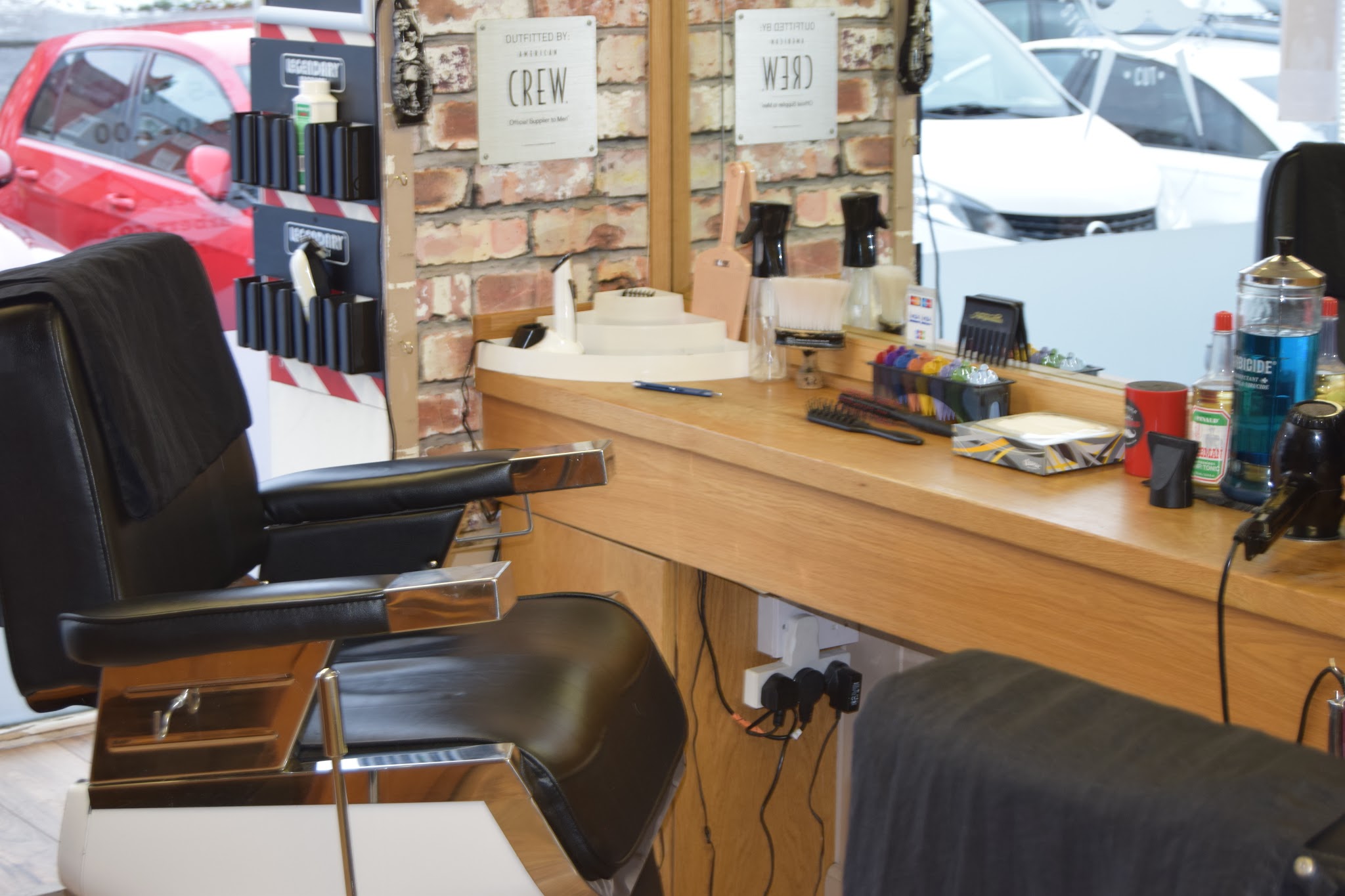 A barber station with a leather chair and mirror against exposed brick, looking out over Market Place