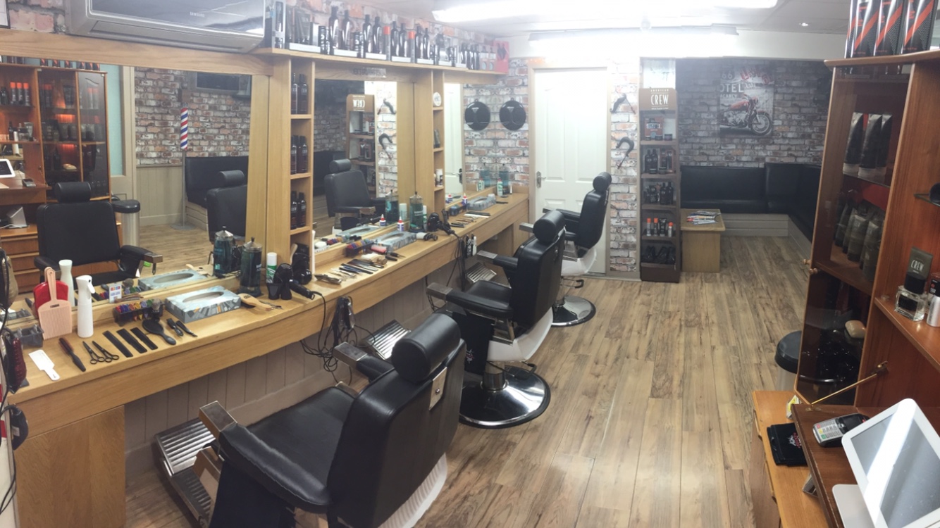 Wide view of the barber room: wooden counters, three barber chairs and a wood floor