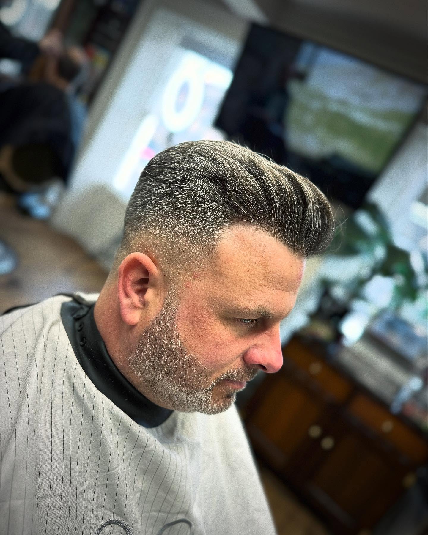 Swept back grey cut with a fade and a trimmed beard